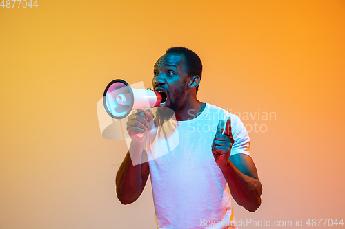 Image of African-american man\'s portrait isolated on gradient orange studio background in neon light
