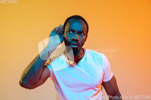 Image of African-american man\'s portrait isolated on gradient orange studio background in neon light