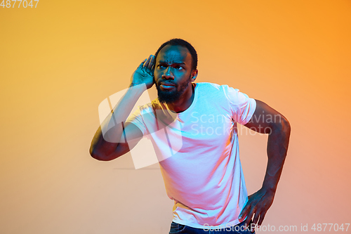 Image of African-american man\'s portrait isolated on gradient orange studio background in neon light