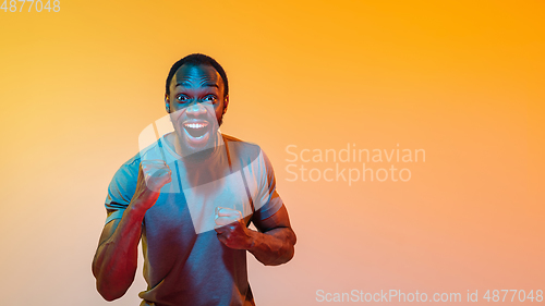 Image of African-american man\'s portrait isolated on gradient orange studio background in neon light