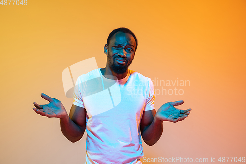 Image of African-american man\'s portrait isolated on gradient orange studio background in neon light