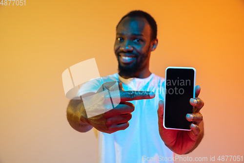 Image of African-american man\'s portrait isolated on gradient orange studio background in neon light