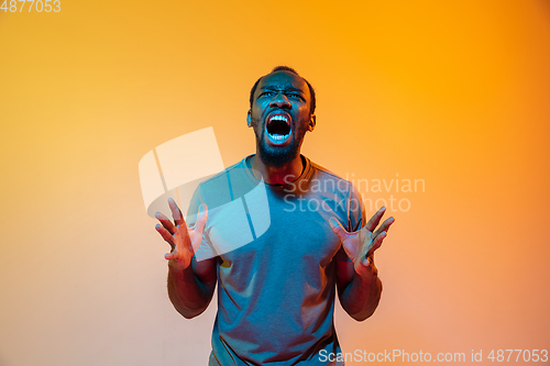 Image of African-american man\'s portrait isolated on gradient orange studio background in neon light