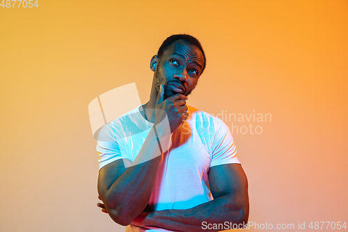Image of African-american man\'s portrait isolated on gradient orange studio background in neon light