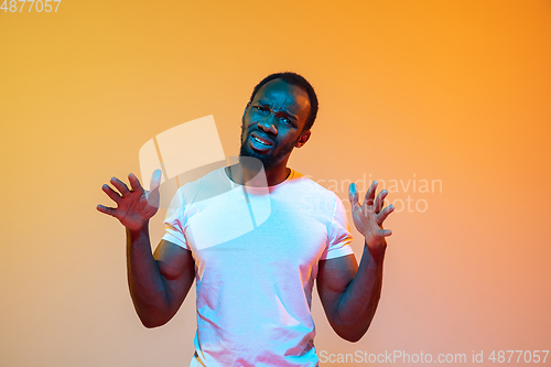 Image of African-american man\'s portrait isolated on gradient orange studio background in neon light