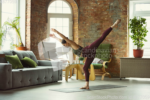 Image of Sporty young woman practicing yoga at home