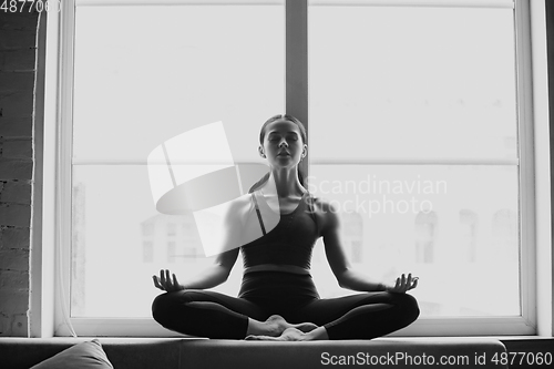 Image of Sporty young woman practicing yoga at home