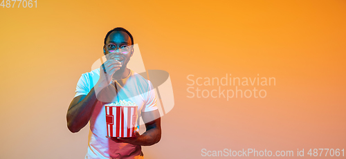 Image of African-american man\'s portrait isolated on gradient orange studio background in neon light