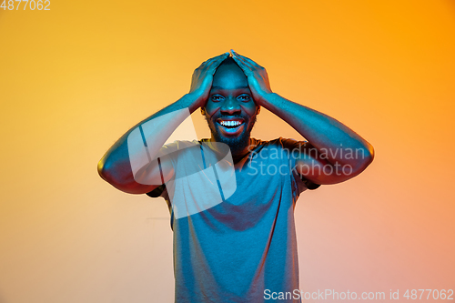 Image of African-american man\'s portrait isolated on gradient orange studio background in neon light