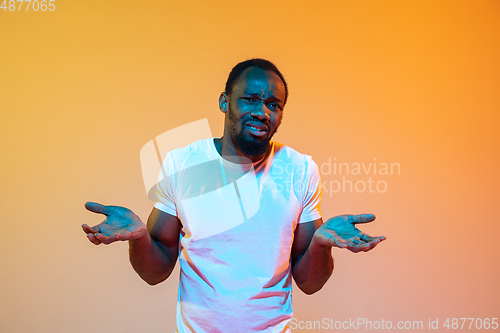 Image of African-american man\'s portrait isolated on gradient orange studio background in neon light