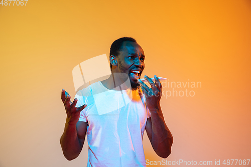 Image of African-american man\'s portrait isolated on gradient orange studio background in neon light