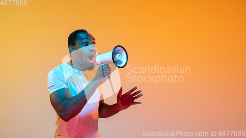 Image of African-american man\'s portrait isolated on gradient orange studio background in neon light