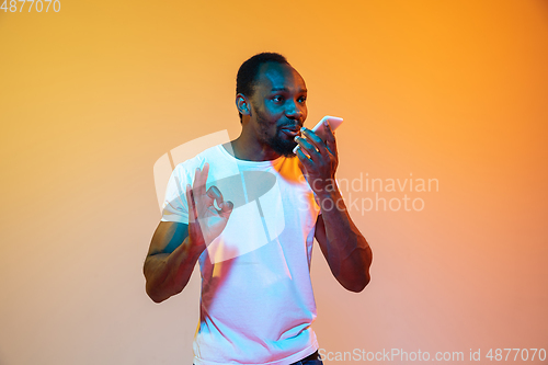 Image of African-american man\'s portrait isolated on gradient orange studio background in neon light
