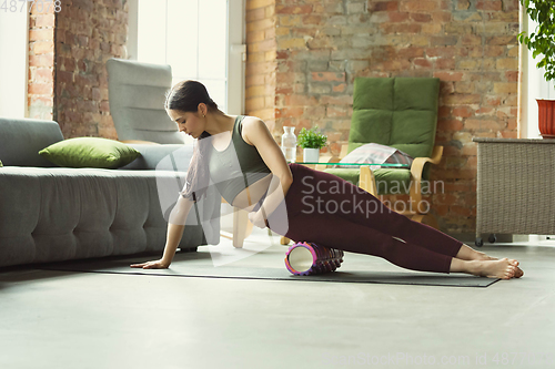 Image of Sporty young woman practicing yoga at home