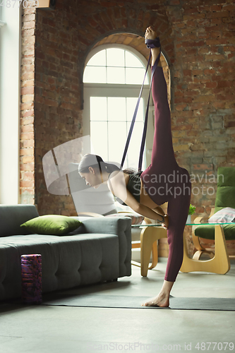 Image of Sporty young woman practicing yoga at home