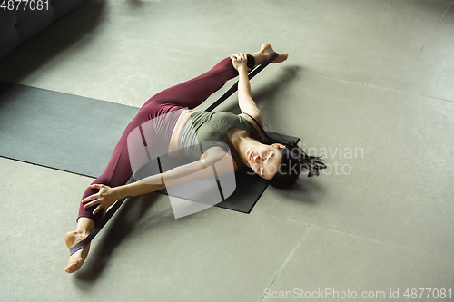 Image of Sporty young woman practicing yoga at home
