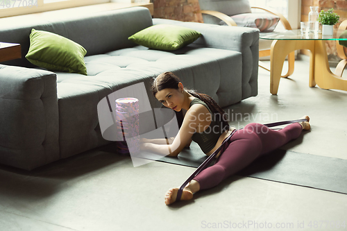 Image of Sporty young woman practicing yoga at home