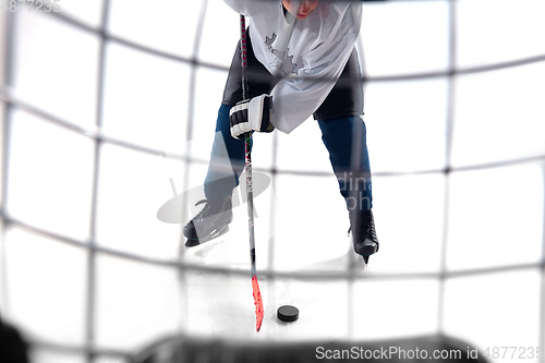 Image of Unrecognizable male hockey player with the stick on ice court and white background