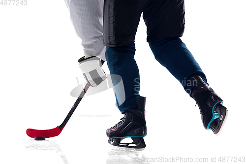 Image of Unrecognizable male hockey player with the stick on ice court and white background