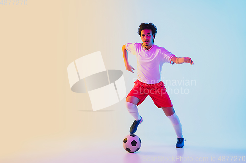 Image of Football or soccer player on gradient background in neon light - motion, action, activity concept