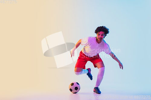 Image of Football or soccer player on gradient background in neon light - motion, action, activity concept