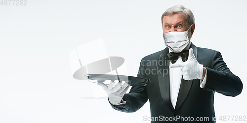 Image of Elegance senior man waiter in protective face mask on white background. Flyer with copyspace.