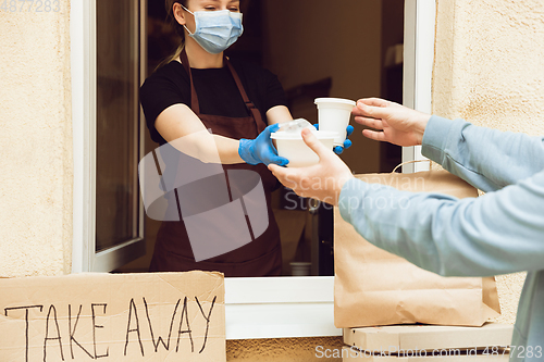 Image of Woman preparing drinks and meals, wearing protective face mask and gloves. Contactless delivery service during quarantine coronavirus pandemic. Take away only concept.