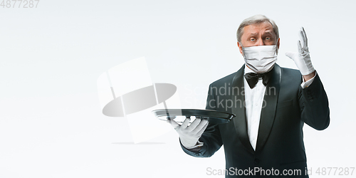 Image of Elegance senior man waiter in protective face mask on white background. Flyer with copyspace.