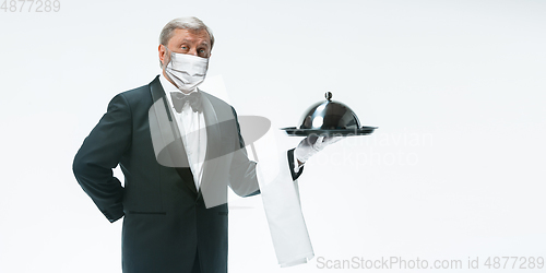 Image of Elegance senior man waiter in protective face mask on white background. Flyer with copyspace.