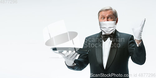 Image of Elegance senior man waiter in protective face mask on white background. Flyer with copyspace.