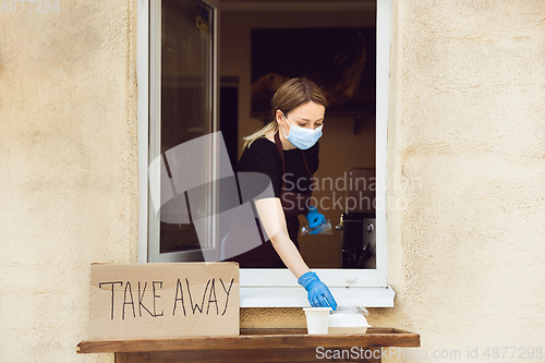 Image of Woman preparing drinks and meals, wearing protective face mask and gloves. Contactless delivery service during quarantine coronavirus pandemic. Take away only concept.