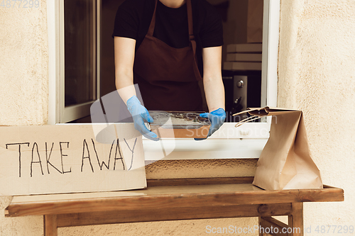 Image of Woman preparing drinks and meals, wearing protective face mask and gloves. Contactless delivery service during quarantine coronavirus pandemic. Take away only concept.