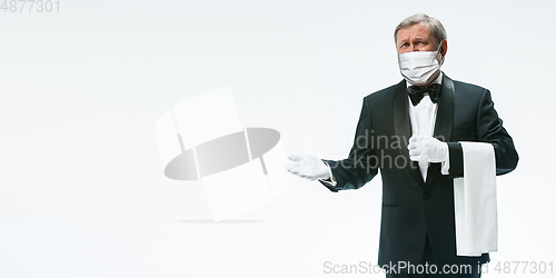 Image of Elegance senior man waiter in protective face mask on white background. Flyer with copyspace.