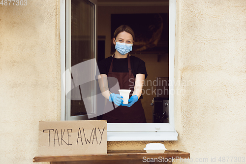 Image of Woman preparing drinks and meals, wearing protective face mask and gloves. Contactless delivery service during quarantine coronavirus pandemic. Take away only concept.