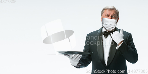 Image of Elegance senior man waiter in protective face mask on white background. Flyer with copyspace.