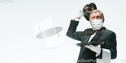 Image of Elegance senior man waiter in protective face mask on white background. Flyer with copyspace.