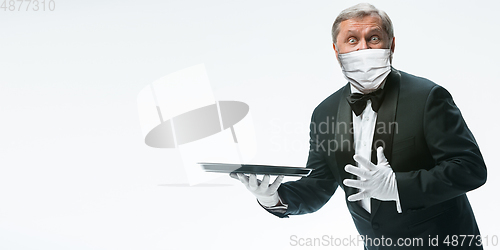 Image of Elegance senior man waiter in protective face mask on white background. Flyer with copyspace.