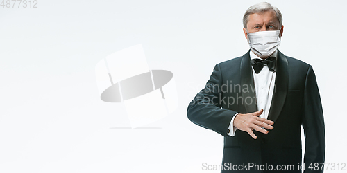 Image of Elegance senior man waiter in protective face mask on white background. Flyer with copyspace.