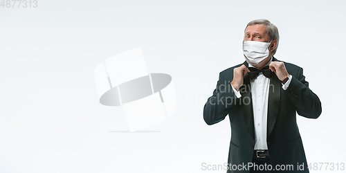 Image of Elegance senior man waiter in protective face mask on white background. Flyer with copyspace.