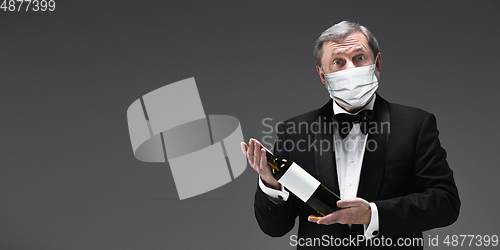 Image of Elegance senior man waiter in protective face mask on gray background. Flyer with copyspace.