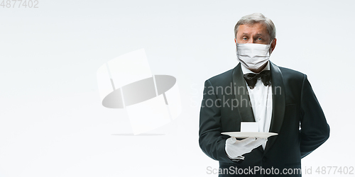 Image of Elegance senior man waiter in protective face mask on white background. Flyer with copyspace.