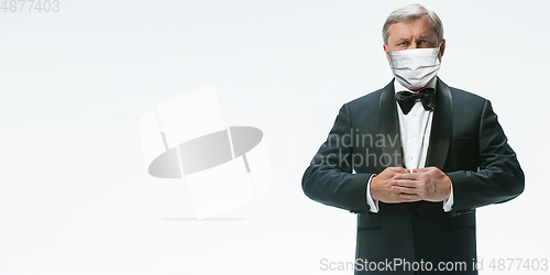 Image of Elegance senior man waiter in protective face mask on white background. Flyer with copyspace.