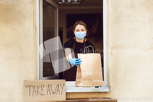 Image of Woman preparing drinks and meals, wearing protective face mask and gloves. Contactless delivery service during quarantine coronavirus pandemic. Take away only concept.