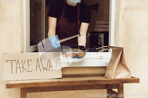 Image of Woman preparing drinks and meals, wearing protective face mask and gloves. Contactless delivery service during quarantine coronavirus pandemic. Take away only concept.