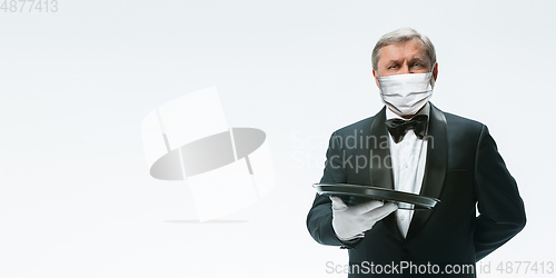 Image of Elegance senior man waiter in protective face mask on white background. Flyer with copyspace.