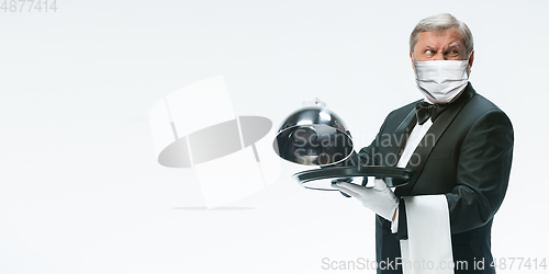 Image of Elegance senior man waiter in protective face mask on white background. Flyer with copyspace.