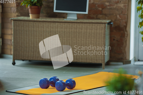 Image of Blue dumbbells lying on yellow yoga mat. Fitness, aerobic. Staying sportive during insulation.