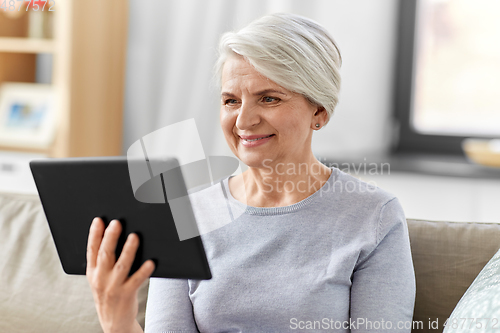 Image of happy senior woman with tablet pc at home