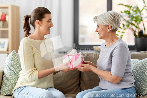 Image of adult daughter giving present to her senior mother