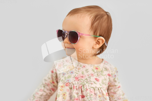 Image of happy little baby girl in sunglasses over grey